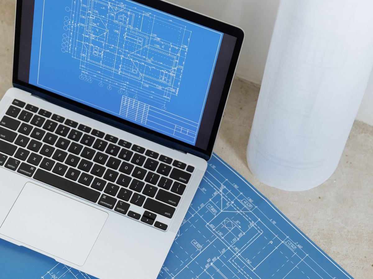 Planos de arquitectura junto a un computador en un escritorio de trabajo